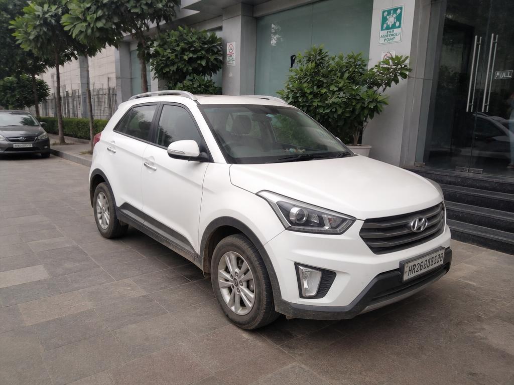 White compact SUV crossover parked in front of an office building entrance